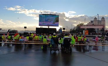 en gruppe mennesker som sitter på en benk foran en scene