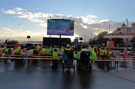 en gruppe mennesker som sitter på en benk foran en scene