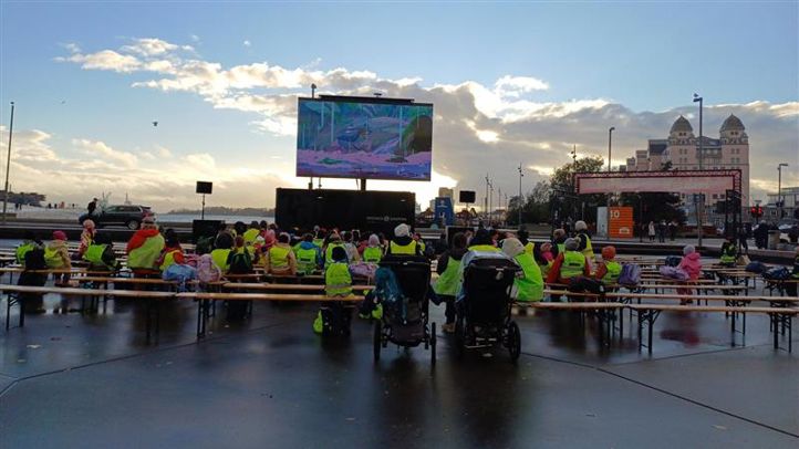 en gruppe mennesker som sitter på en benk foran en scene